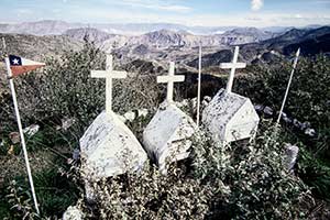 drei Gräber vor Gebirgskulisse