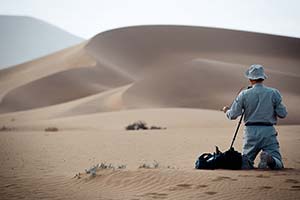 Fotograf kniet im Sand der Namib