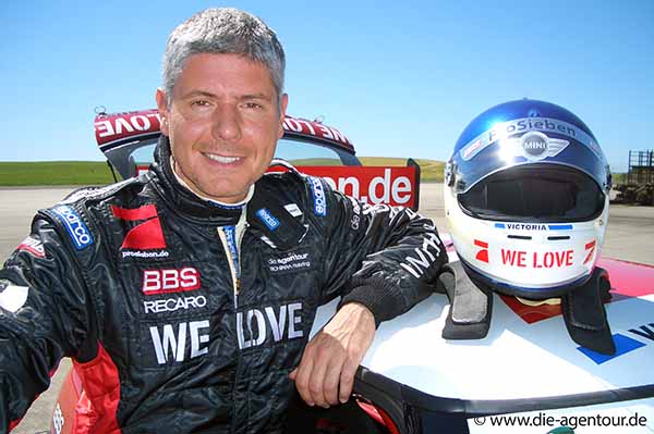 Michael Marx steht neben Rennwagen mit Helm auf dem Dach